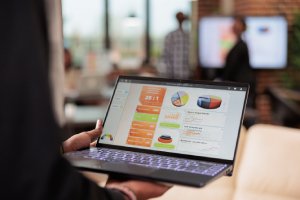 Graphic designer reviewing brand performance charts and visual reports on laptop